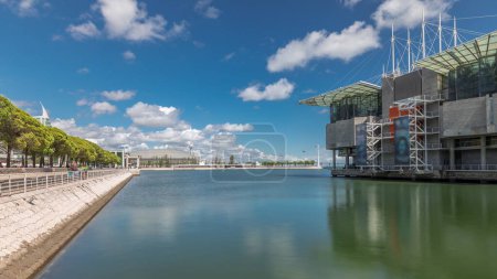 Panorama mit Zeitraffer des Lissabon Oceanarium, gelegen im Park der Nationen oder Parque das Nacoes. Das größte Indoor-Aquarium Europas. Uferpromenade mit grünen Bäumen und Wolken am blauen Himmel. Portugal