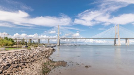 Photo for Panorama showing waterfront and the Vasco da Gama Bridge timelapse. Cable-stayed longest bridge flanked by viaducts and range views that spans the Tagus River in Park of Nations in Lisbon, Portugal - Royalty Free Image