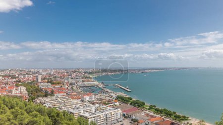 Panorama mit Luftaufnahme des Yachthafens und der Innenstadt in Setubal, Portugal. Rote Dächer und Uferpromenade mit Booten und Schiffen von oben. Bewölkter Himmel an sonnigem Tag