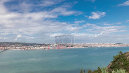 Panorama showing Lisbon cityscape and Tagus river timelapse, aerial view of Old Town Alfama with landmark suspension 25 of April bridge from viewpoint of Cristo Rei in Almada. Portugal