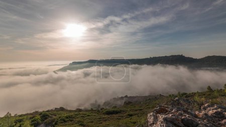 Téléchargez les photos : Panorama montrant la vue aérienne de la ville de Sesimbra et le port couvert par le brouillard timelapse, Portugal. Paysage supérieur au-dessus des nuages et coucher du soleil. Resort dans le quartier de Setubal - en image libre de droit