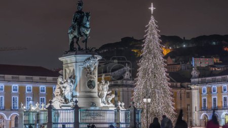 Photo for Commerce square illuminated and decorated at Christmas time in Lisbon night timelapse. Commercio square with Christmas tree and Jose I monument. People tourists crowd around. Holiday times. Portugal - Royalty Free Image