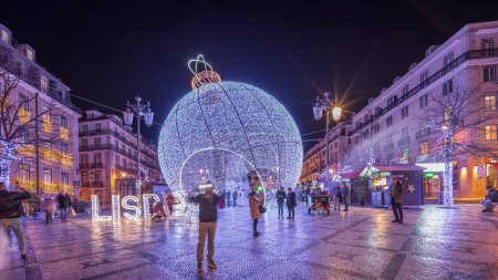 Panorama mit Weihnachtsdekoration mit großer Kugel auf dem Luis De Camoes Platz (Praca Luis de Camoes) im Zeitraffer. Einer der größten Plätze der portugiesischen Stadt Lissabon am Abend beleuchtet