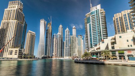 Foto de Dubai Marina modernas torres altas reflejadas en el agua del paseo marítimo timelapse hyperlapse, Emiratos Árabes Unidos. Distrito en Dubai y un canal artificial. Cielo nublado azul - Imagen libre de derechos