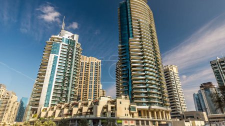Téléchargez les photos : Dubai Marina tours modernes reflétées dans l'eau de la promenade timelapse, Émirats arabes unis. Quartier de Dubaï et canal artificiel. Ciel nuageux bleu - en image libre de droit