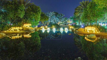 Foto de Lago con tigres y árboles. Dubai Glow Garden con árboles y esculturas iluminadas. Es una arquitectura de estado del arte con arquitectura amigable con el medio ambiente, creando varias estructuras - Imagen libre de derechos