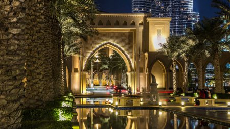 Entrance of Hotels with arch, offices and Souk in downtown night timelapse hyperlapse in Dubai, UAE Palms and reflections in water of fountain pool
