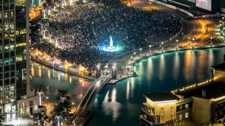 Top-Nahaufnahme der Brücke über den künstlichen See und viele Menschen im Park mit Handdenkmal Zeitraffer in Dubai Downtown vor Silvesterfeier, Vereinigte Arabische Emirate.