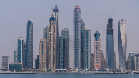Téléchargez les photos : Dubai Marina skyline day to night transition timelapse panorama as seen from Palm Jumeirah in Dubai, UAE. Cette partie de Dubaï a plus de gratte-ciel sur 50 histoires - en image libre de droit