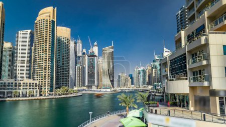 Téléchargez les photos : Dubai Marina canal avec des yachts et des tours modernes reflétés dans l'eau verte du pont à Dubai timelapse hyperlapse, Émirats arabes unis. Quartier avec canal artificiel - en image libre de droit