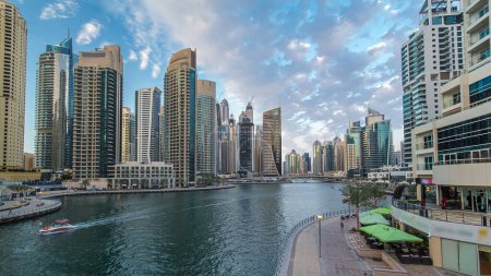 Téléchargez les photos : Dubai Marina waterfront with towers and yachts from bridge in Dubai day to night transition timelapse, Émirats arabes unis. Quartier avec canal artificiel et gratte-ciel autour - en image libre de droit