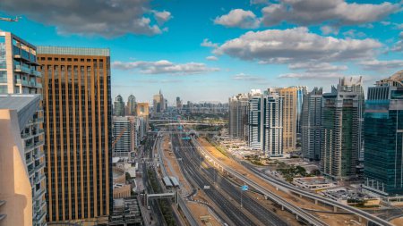 Foto de Vista aérea de los rascacielos del puerto deportivo de Dubái y las torres de los lagos Jumeirah timelapse con tráfico en la carretera sheikh zayed. Tiempo de puesta del sol con cielo azul nublado - Imagen libre de derechos