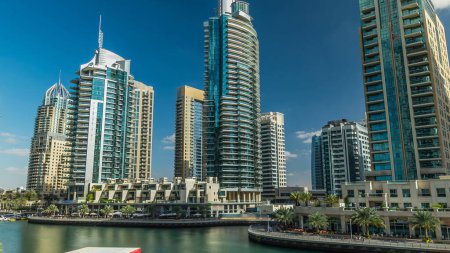 Téléchargez les photos : Dubai Marina canal panorama avec des yachts et des tours modernes reflétés dans l'eau verte du front de mer à Dubai timelapse hyperlapse, Émirats arabes unis. Canal artificiel et gratte-ciel autour - en image libre de droit
