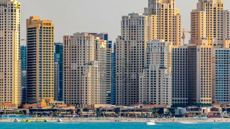Foto de Jumeirah Beach Residence horizonte al atardecer como se ve desde la palma jumeirah con timelapse mar. Muchos rascacielos a la luz de la tarde. Dubai, Emiratos Árabes Unidos - Imagen libre de derechos