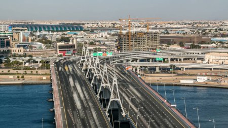 Téléchargez les photos : Pont de passage de la baie d'affaires avec timelapse de la circulation, pont à 13 voies, au-dessus du ruisseau Dubai près de l'aéroport. Ciel nuageux bleu avant le coucher du soleil - en image libre de droit