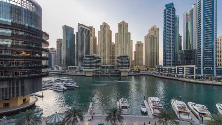Foto de Dubai Marina waterfront con torres y yates cerca de restaurantes desde el balcón del centro comercial en Dubai día a noche transición aérea timelapse, Emiratos Árabes Unidos. - Imagen libre de derechos
