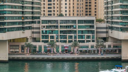 Téléchargez les photos : Dubai Marina front de mer avec tours et restaurants avec palmiers du centre commercial à Dubai transition aérienne timelapse, Émirats arabes unis. - en image libre de droit
