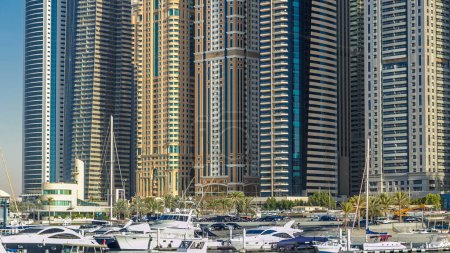 Foto de Vista de cerca desde el paseo marítimo en Dubai Marina torres modernas más altas y yates flotantes y barcos timelapse al atardecer, Emiratos Árabes Unidos. - Imagen libre de derechos