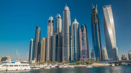 Foto de Dubai Marina torres modernas más altas y yates flotantes y barcos timelapse hiperlapso desde la zona de paseo antes del atardecer, Emiratos Árabes Unidos. - Imagen libre de derechos