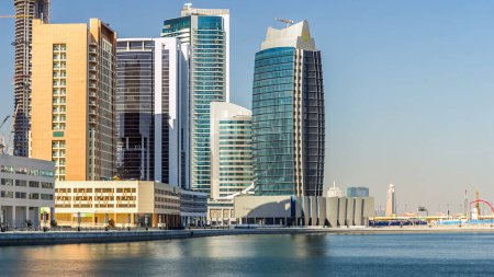 Téléchargez les photos : Skyline de la baie d'affaires de Dubaï avec des gratte-ciel le jour timelapse avec ciel bleu et réflexion dans l'eau. - en image libre de droit