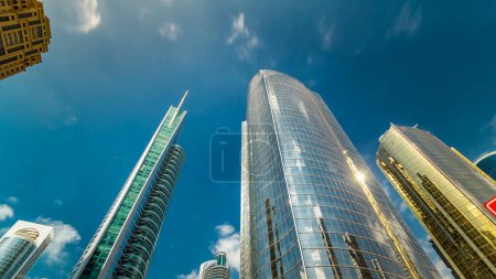 Photo for Look up panoramic and perspective view to steel glass high rise building skyscrapers hyperlapse, business concept of successful industrial architecture, Dubai, UAE. Blue cloudy sky at sunny day - Royalty Free Image