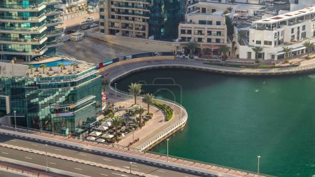 Aerial view timelapse of Dubai Marina promenade and canal with floating yachts and boats at day time before sunset in Dubai, UAE. Torres modernas, puente y tráfico en la carretera