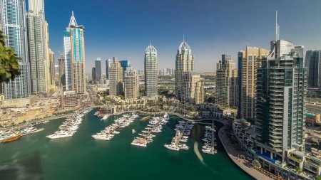 Téléchargez les photos : Vue aérienne timelapse de Dubai Marina promenade et canal avec des yachts flottants et des bateaux à la veille du coucher du soleil à Dubaï, EAU. Tours modernes et circulation sur la route, les ombres bougent très vite - en image libre de droit