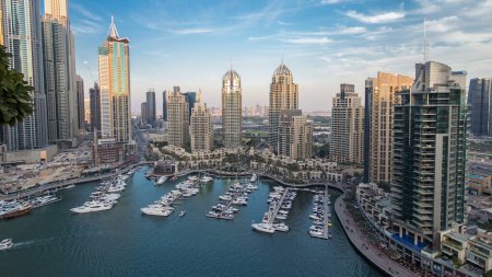 Téléchargez les photos : Vue aérienne de jour comme de nuit sur la promenade et le canal de la marina de Dubaï avec des yachts flottants et des bateaux après le coucher du soleil à Dubaï, Émirats arabes unis. Tours modernes et la circulation sur la route d'en haut - en image libre de droit