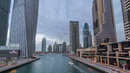 Foto de Dubai Marina waterfront with towers and yachts from bridge day to night transition timelapse, Emiratos Árabes Unidos. Rascacielos y canal después del atardecer - Imagen libre de derechos