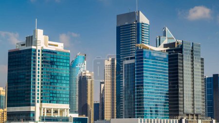 Téléchargez les photos : Skyline de la baie d'affaires de Dubaï avec des gratte-ciel modernes le jour timelapse avec ciel nuageux bleu. Immeubles de bureaux autour - en image libre de droit
