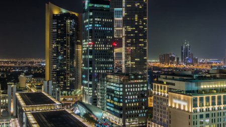Téléchargez les photos : Dubaï architecture du centre-ville la nuit timelapse. Vue aérienne de nombreux gratte-ciel près de la route Sheikh Zayed. Tours de bureaux éclairées avec fenêtres et circulation lumineuses - en image libre de droit