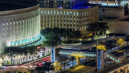 Téléchargez les photos : Vue aérienne du trafic près du centre commercial la nuit dans la Marina de Dubaï à Dubaï, Émirats arabes unis. Des tours modernes lumineuses avec des lumières clignotantes et la circulation sur la route, le tramway et la ligne de métro. - en image libre de droit