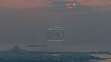 Foto de Arriba de cerca vista aérea de Abu Dhabi Skyline al atardecer con nubes y cielo rojo timelapse, Emiratos Árabes Unidos - Imagen libre de derechos