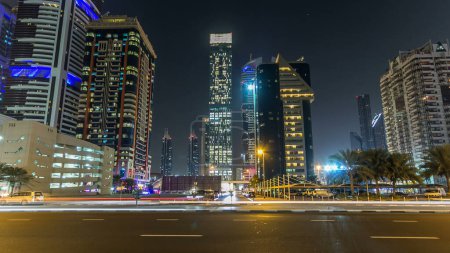 Foto de El centro de Dubái torres noche timelapse hiperlapso. Vista de Sheikh Zayed carretera con rascacielos altos. Tráfico en la carretera y estacionamiento de varios pisos. Luces y senderos parpadeantes - Imagen libre de derechos