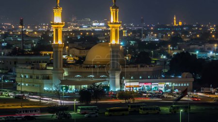 Dubais Skyline aus der Luft mit nachts beleuchteter Moschee und Geschäften in der Nähe im Zeitraffer von oben. Dubai, Vereinigte Arabische Emirate.