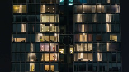 Téléchargez les photos : Clignotant lumière dans la fenêtre de l'immeuble de plusieurs étages de verre et d'acier éclairage et les gens dans timelapse vue rapprochée. Dubai, Émirats arabes unis - en image libre de droit