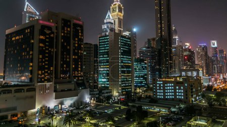 Foto de El centro de Dubai torres de noche timelapse. Vista aérea de la carretera Sheikh Zayed con ventanas brillantes en rascacielos. Tráfico en la carretera. Luces y senderos parpadeantes - Imagen libre de derechos