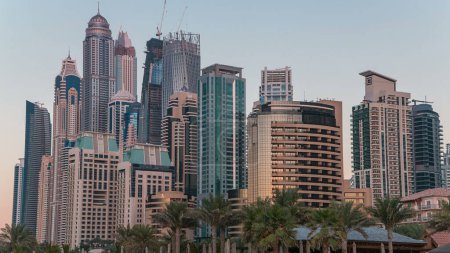 Photo for Modern skyscrapers day to night transition timelapse of Dubai marina from jumeirah beach residence in Dubai, JBR - artificial canal city, carved along a 3 km on Persian Gulf shoreline. - Royalty Free Image