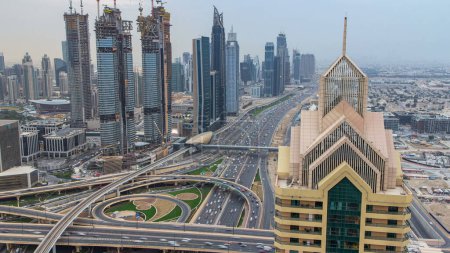 Téléchargez les photos : Des gratte-ciel modernes et des autoroutes du soir animées de jour comme de nuit se succèdent dans le luxueux centre-ville de Dubaï. Vue aérienne depuis le toit de la tour. Circulation routière. Dubai, Émirats arabes unis - en image libre de droit