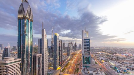 Foto de Dubai arquitectura céntrica día a noche timelapse transición. Vista aérea superior sobre la carretera Sheikh Zayed con rascacielos iluminados y tráfico. Hermoso cielo nublado - Imagen libre de derechos