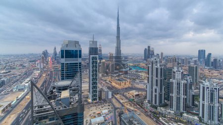 Foto de Skyline panorámico de Dubai día a noche timelapse transición, Emiratos Árabes Unidos. Famosos rascacielos vista aérea desde la azotea de la torre. Hermoso cielo nublado. Coloridos viajes y fondo de negocios - Imagen libre de derechos