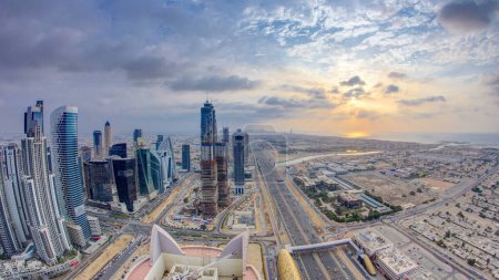 Téléchargez les photos : Tours de la baie d'affaires de Dubaï avec antenne coucher de soleil. Vue sur le toit de certains gratte-ciel et de nouvelles tours en construction. Canal d'eau avec ponts et circulation routière Cheikh Zayed. Ciel nuageux coloré en soirée - en image libre de droit