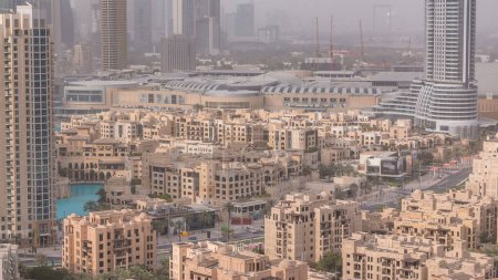 Downtown Dubai Skyline mit Wohntürmen im Zeitraffer, Blick vom Dach. Brunnen und Einkaufszentrum auf einem Hintergrund