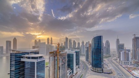 Foto de Dubai torres de la bahía de negocios al atardecer panorama timelapse aérea. Vista de la azotea de algunos rascacielos y nuevas torres en construcción. - Imagen libre de derechos