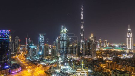 Téléchargez les photos : Paysage urbain aérien timelapse pendant toute la nuit avec une architecture moderne éclairée avec des lumières éteintes dans le centre-ville de Dubaï, Émirats arabes unis. Vue sur le quartier financier éclairée depuis le toit - en image libre de droit