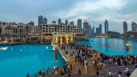 Photo for The bridge near the biggest musical fountain in Dubai day to night transition timelapse. Dubai, UAE. Top view from balcony. People walking around - Royalty Free Image