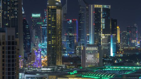 Foto de Aerial cityscape timelapse por la noche con arquitectura moderna iluminada en el centro de Dubai, Emiratos Árabes Unidos. Iluminada vista del distrito financiero desde arriba - Imagen libre de derechos