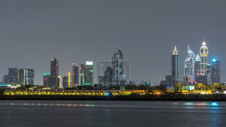 Moderne Skyline Dubais in der Nacht mit beleuchteten Wolkenkratzern im Finanzviertel über der Wasseroberfläche. Blick von der Insel Daria auf Dubai Downtown und Businessbucht