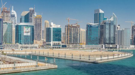 Photo for Panoramic timelapse view of business bay and downtown area with island of Dubai. Modern skyscrapers reflected in water and blue sky. Top view from bridge - Royalty Free Image