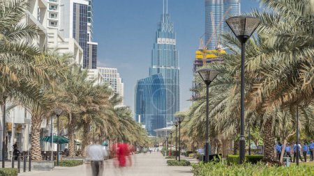 Vue imprenable sur la baie d'affaires et le centre-ville de Dubaï. gratte-ciel et nuages modernes sur ciel bleu. Les gens marchent parmi les palmiers
